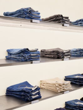 Detailaufnahme: Gefaltete Denim-Jeans im Regal — sichtbare Nahtführung und Denim-Textur. Produkt-Fotografie