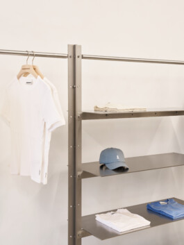 Detail: Edelstahlregal mit aufgehängten Kleidungsstücken — Stoff- und Metallkontrast. Produkt-Fotografie